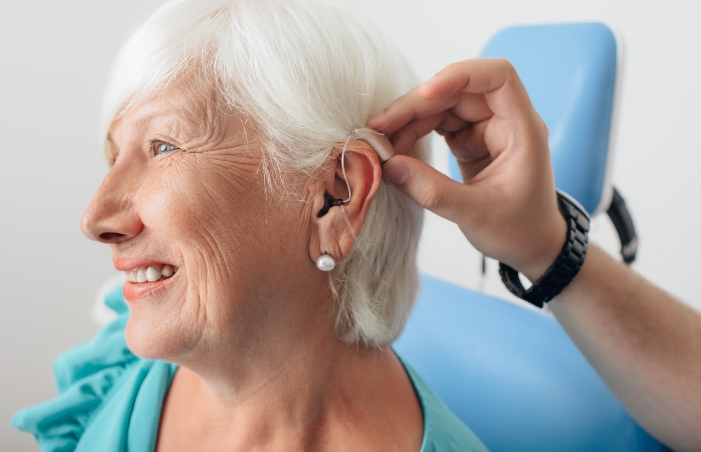 A hearing aid being placed on an elderly woman