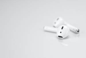 A pair of Apple AirPods sitting on a light grey surface