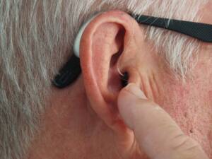 A man pointing to a hearing device in his ear
